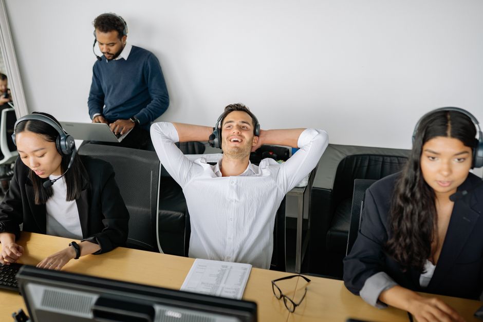 Profissionais de call center em estações de trabalho, mostrando trabalho em equipe e comunicação.