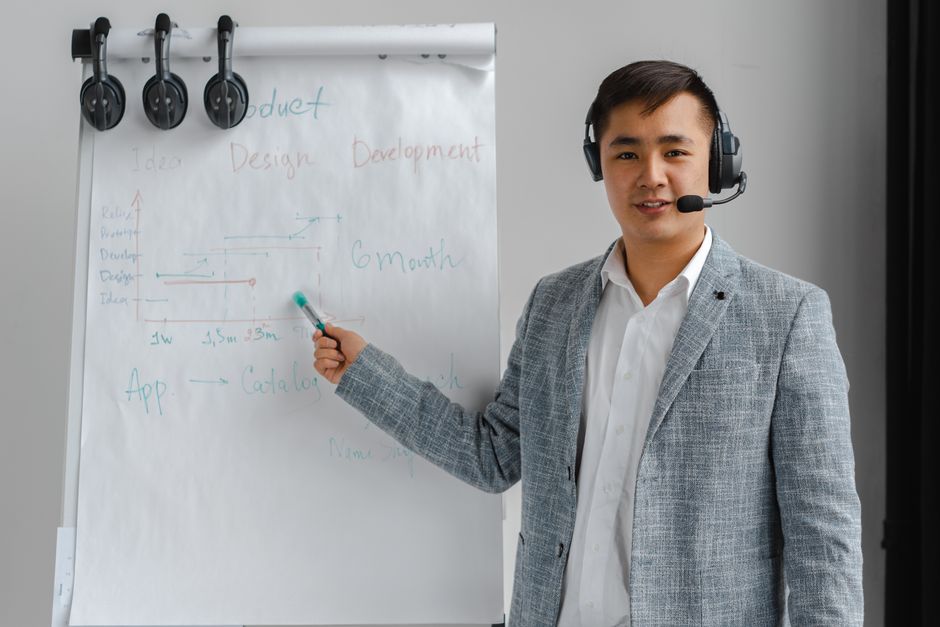 Um profissional de terno com fone de ouvido apresentando em um flip chart.