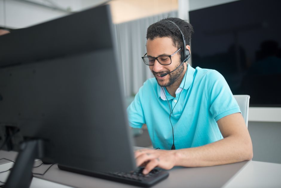 Agente de call center trabalhando em um computador em um ambiente de escritório com um headset.